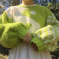 a woman wearing a green sweater and white dress