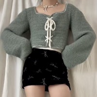 a woman wearing a sweater and black skirt