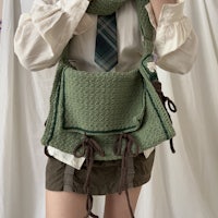 a woman is holding a green knitted bag