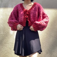 a woman wearing a pink sweater and black skirt
