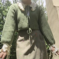 a woman wearing a green sweater and skirt