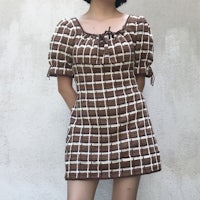 a woman wearing a brown and white checkered dress