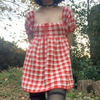 a woman wearing a red and white gingham dress