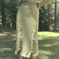 a woman in a green knit skirt standing in the woods
